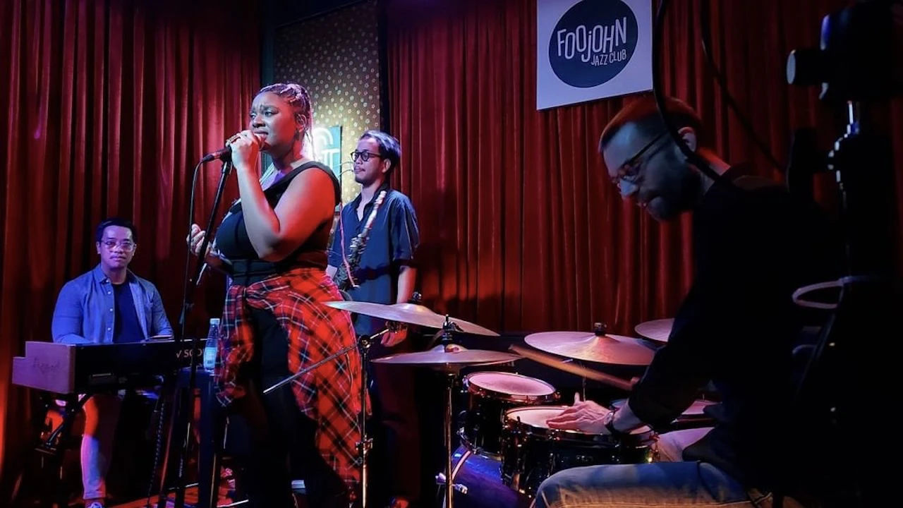 a female jazz singer is singing with her band at Foojohn jazz club