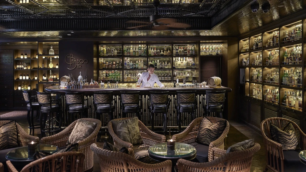 interior of bamboo bar in bangkok displaying the counter, the chairs and the walls covered in bottles for cocktails