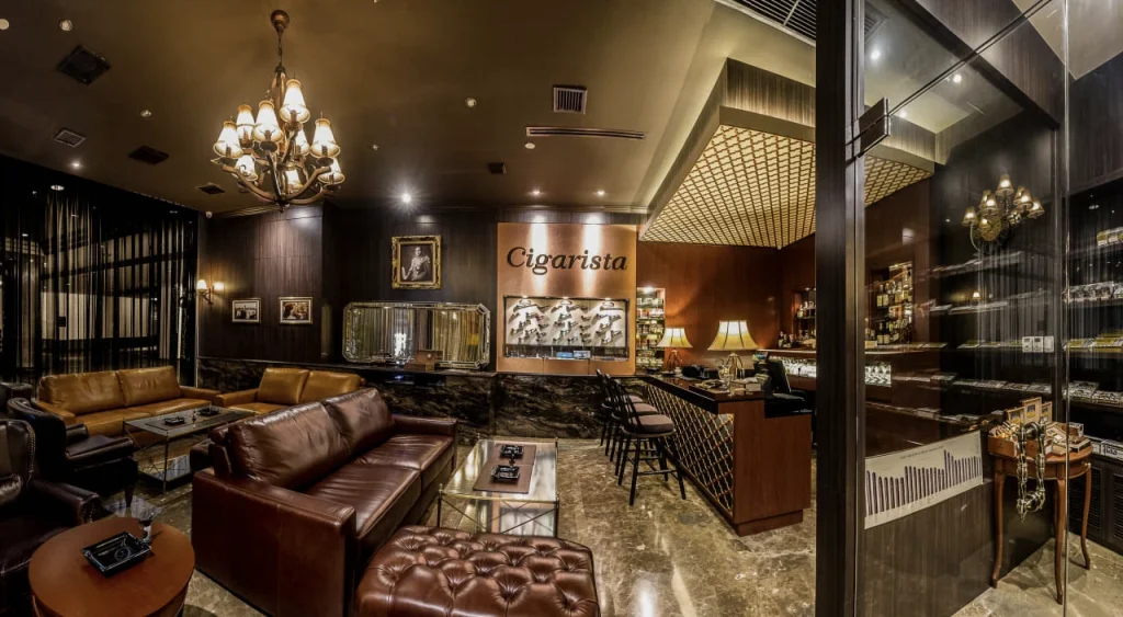 genrous lounge section of cigarista in bangkok with large sofas t osit and enjoy cigars and whisky and a collection of smoking pipes on display