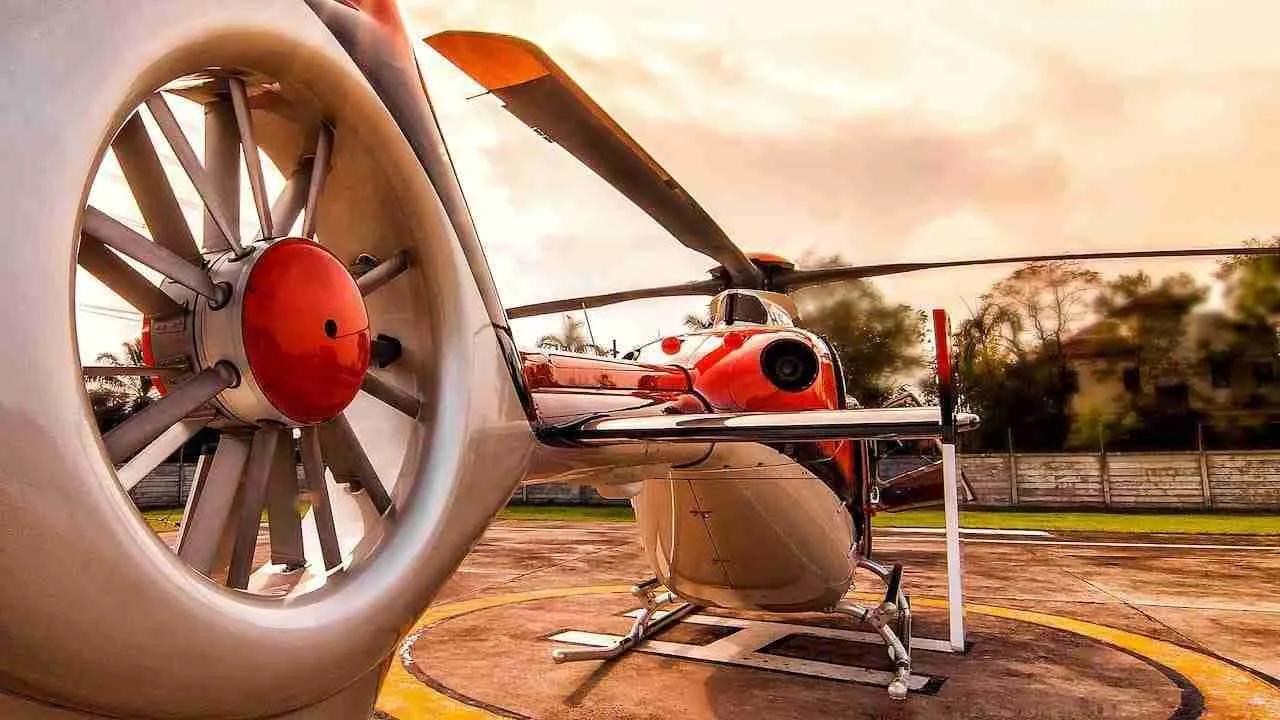 orange helicopter on a helipad in Thailand during the sunset