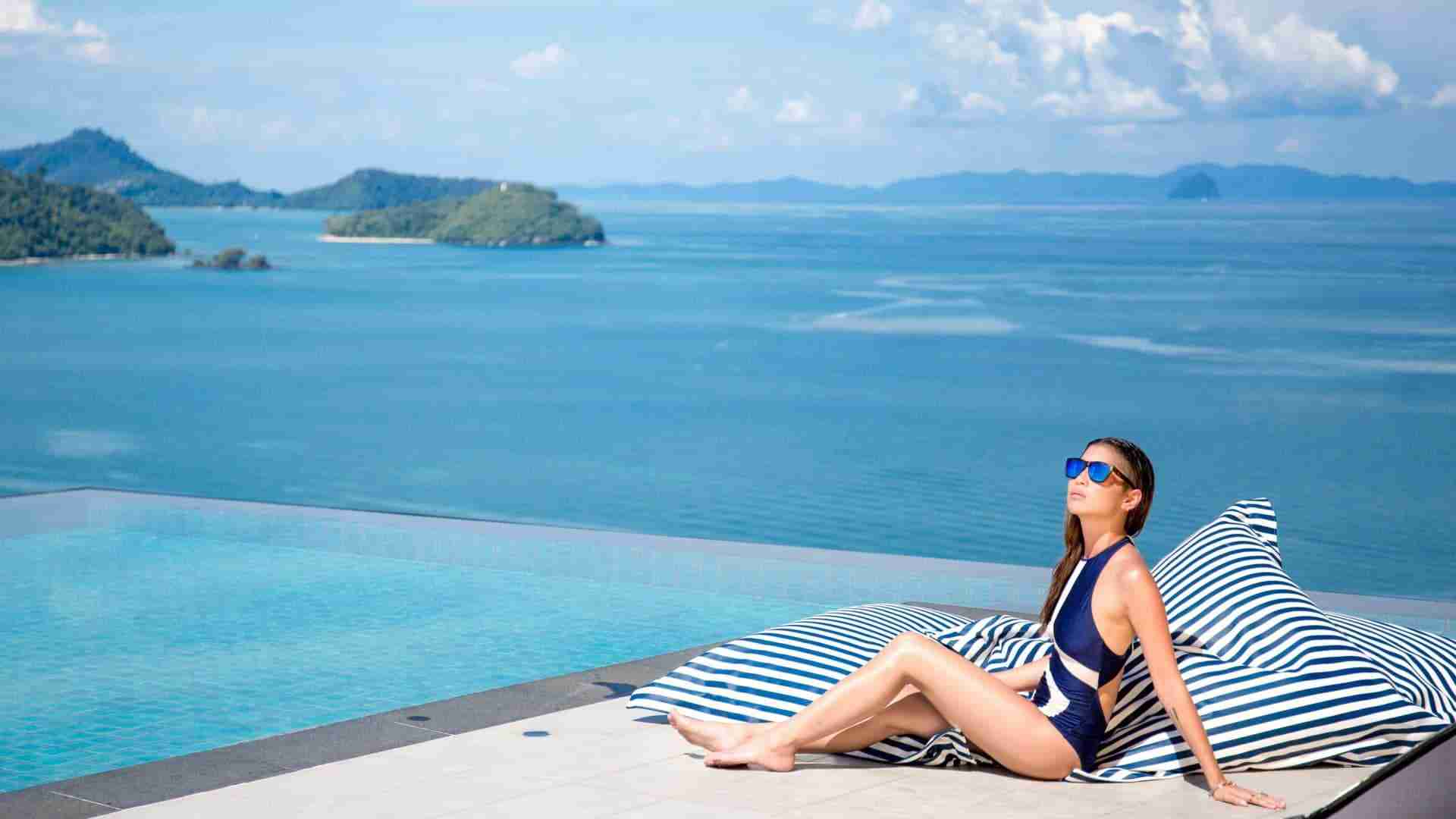 Thai girl by an infinity pool with view over the ocean in Phuket Thailand