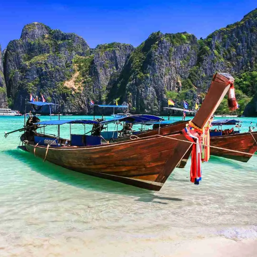longtail boat on blue water and white sand in Thailand