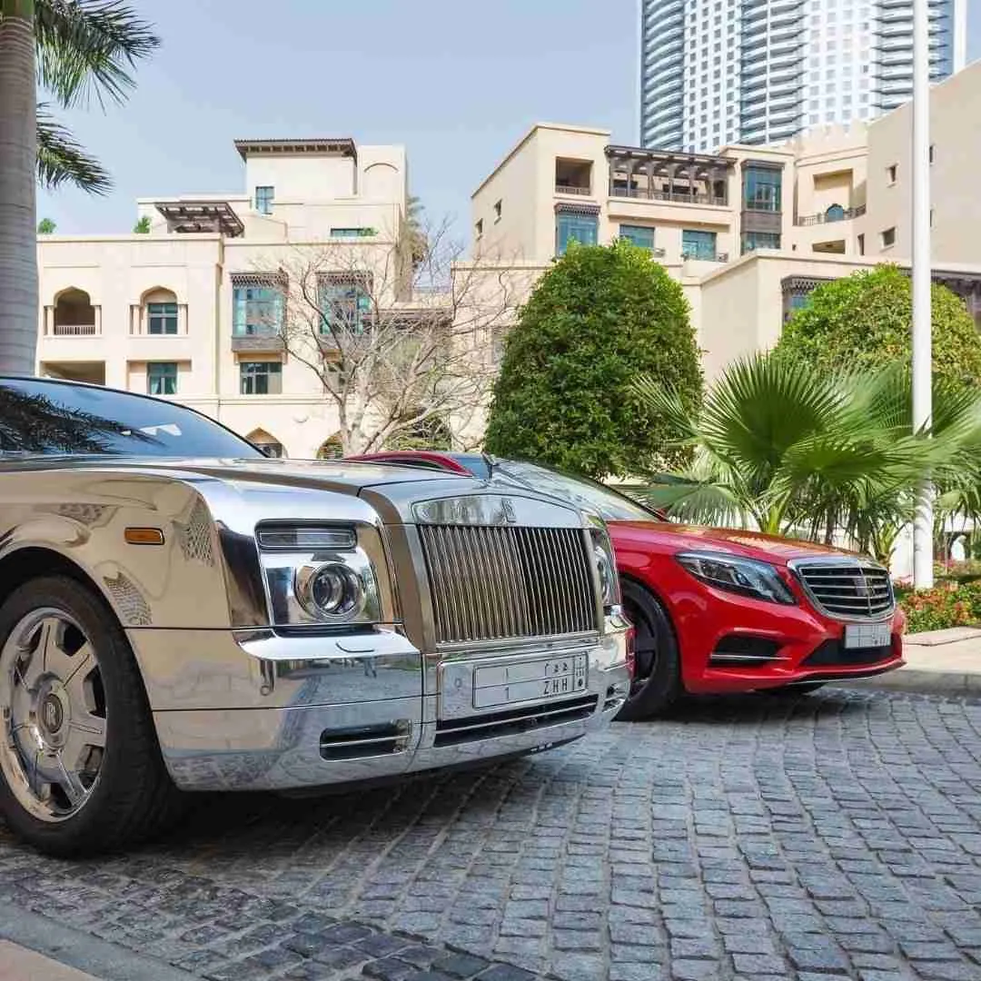 two luxury cars parked in front of a hotel