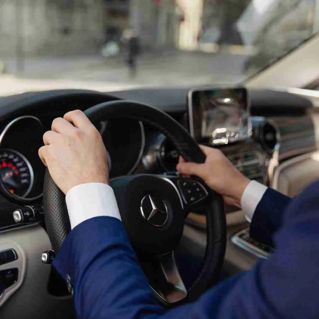 VIP chauffeur hands on the wheel of a mercedes limousine car