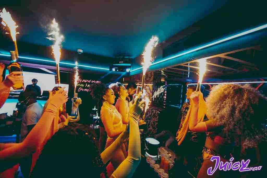 sexy Thai hostesses bringing bottles to a VIP table at Juicy nightclub in Bangkok