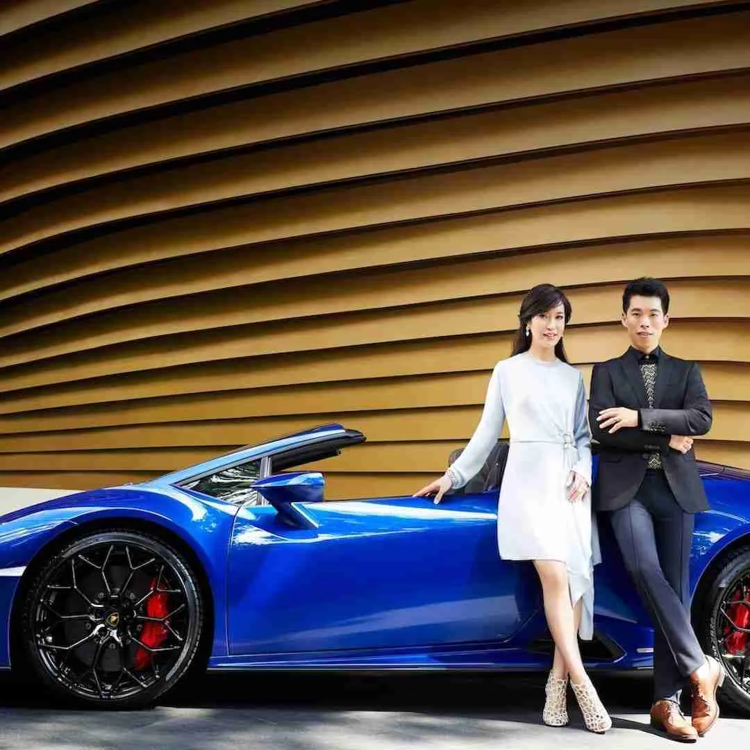 wealthy couple next to a luxury car