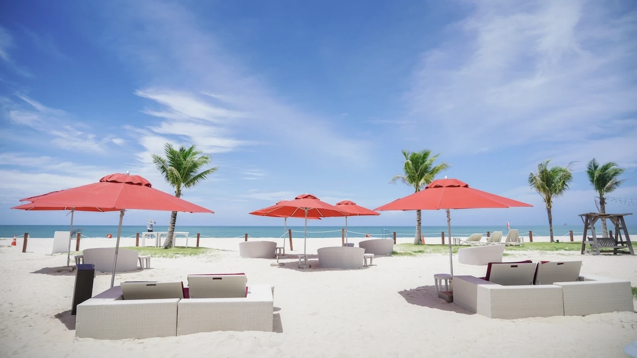 long chairs and red umbrellas on the sand at xana beach club in phuket
