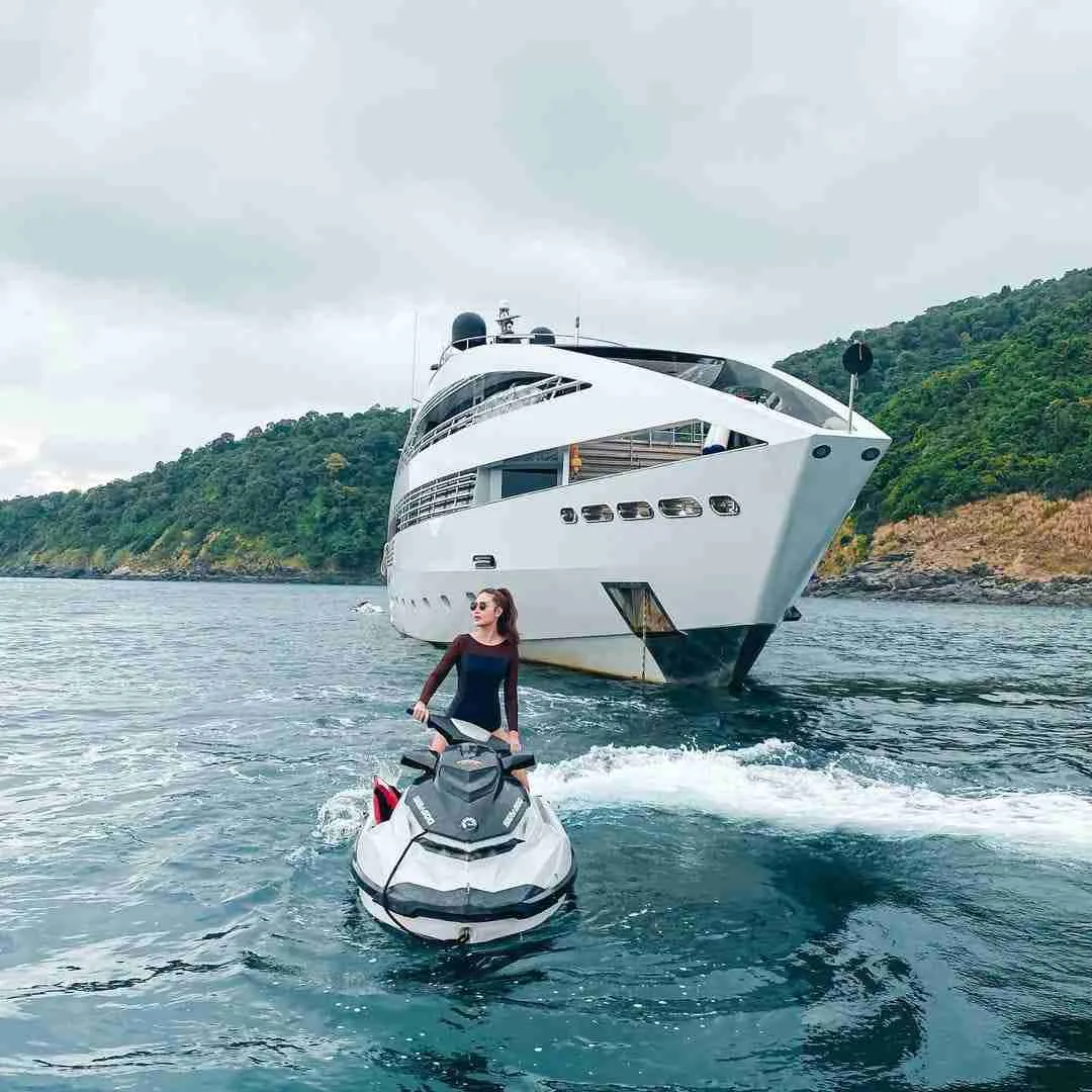 Thai woman riding a jet ski around the Ocean Emerald yacht