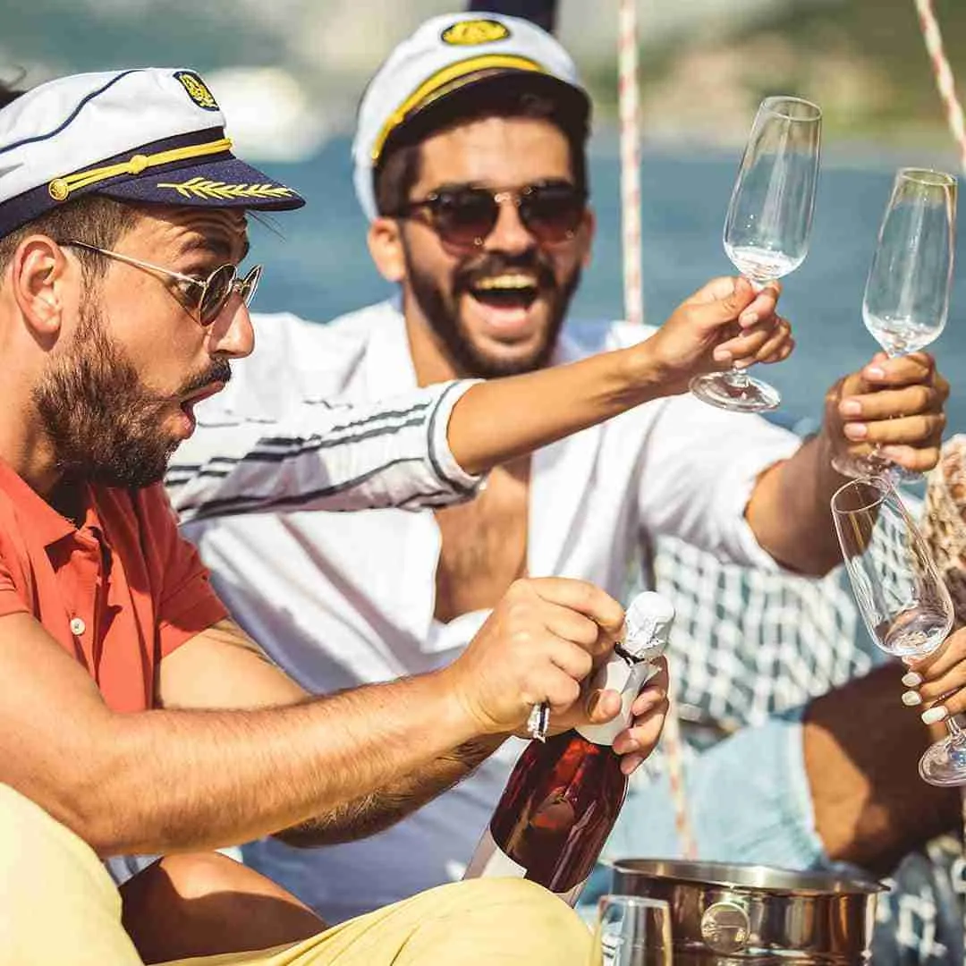 guests with captains hats drinking champagne during a yacht party in Thailand